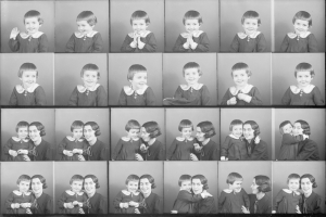 Schwarzes und weißes Foto einer Gruppe von Kindern mit einer Frau in der Mitte, die ein Baby hält und beide warm lächeln