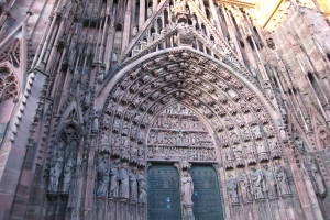 Der Eingang zur Kölner Dom in Köln, Deutschland, mit detaillierten Schnitzereien, Skulpturen und einer großen Tür unten.