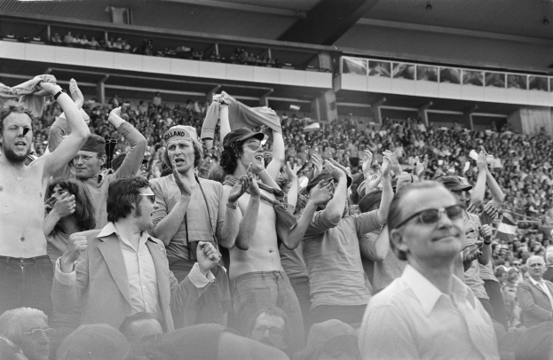 Schwarzes und weißes Foto einer vollen Tribüne mit einigen Zuschauern mit Brille.