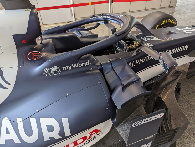 Ein Formel-E-Rennwagen in einem Museum ausgestellt, teilweise zusammengebaut mit Werkzeugen und Materialien, die auf dem Boden verstreut sind.