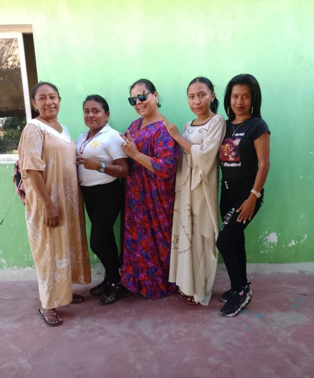 Gruppe von Frauen vor einer grünen Wand mit einem Fenster auf der linken Seite, die an einem Internationalen Frauentag teilnehmen.