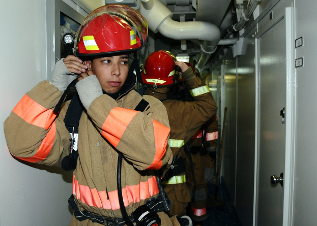 Feuerwehrleute in Uniform in einem Raum mit Rohren und Ausrüstung während eines Übungsbetriebs.