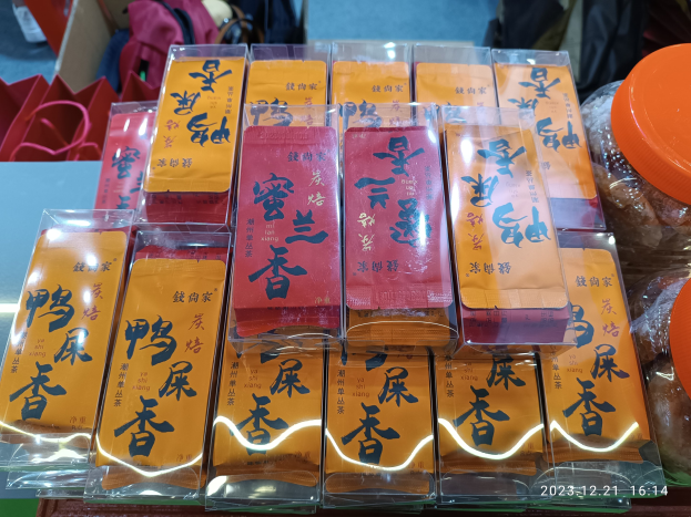 Ein Tisch mit verschiedenen verpackten Lebensmitteln und Gegenständen, mit einer Person im Hintergrund während eines chinesischen Neujahrsfests.