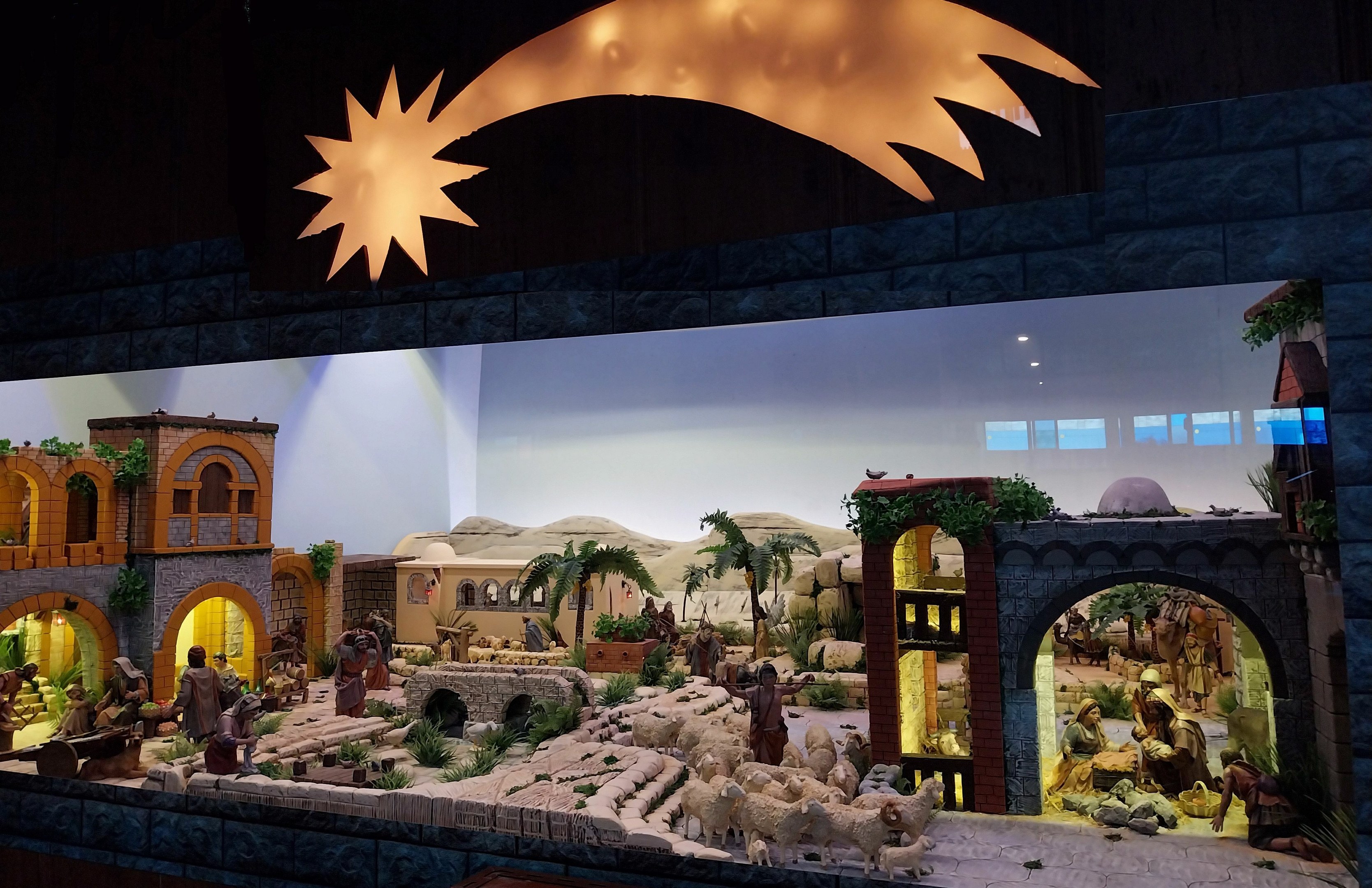 Eine Krippenausstellung im Museum, mit Figuren, Tieren, Gebäuden und Grünpflanzen, beleuchtet von oben.