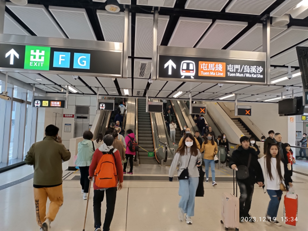 Menschen mit Gepäck durch einen geschlossenen Flughafen gehen, Rolltreppen, Informationsanzeigen, Deckenlichter und Glaswände im Hintergrund sichtbar.