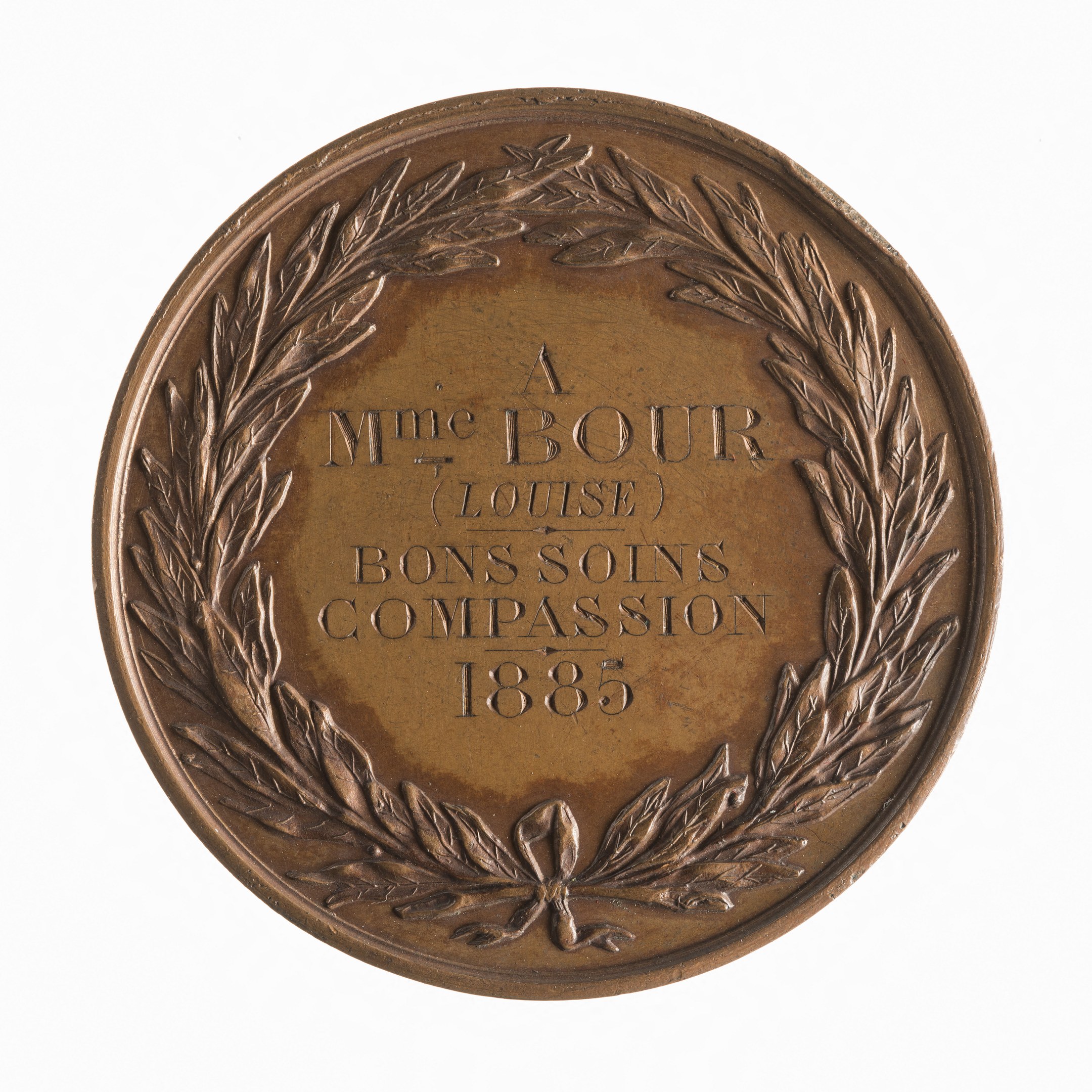 Bronze-Medaille mit Lorbeerkranz und der Aufschrift "Bons Soins Compassion" auf weißem Hintergrund.