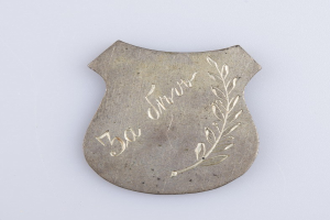 Silbernes Abzeichen mit Lorbeerkranz-Design, beschriftet mit "50. Jubiläum", vor weißem Hintergrund.