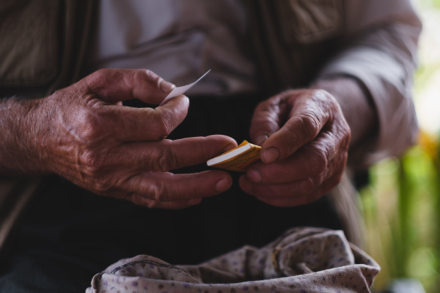 Alter Mann hält ein Blatt Papier in der Hand und sieht besorgt aus, mit einem unscharfen Hintergrund, wahrscheinlich wegen Demenz.