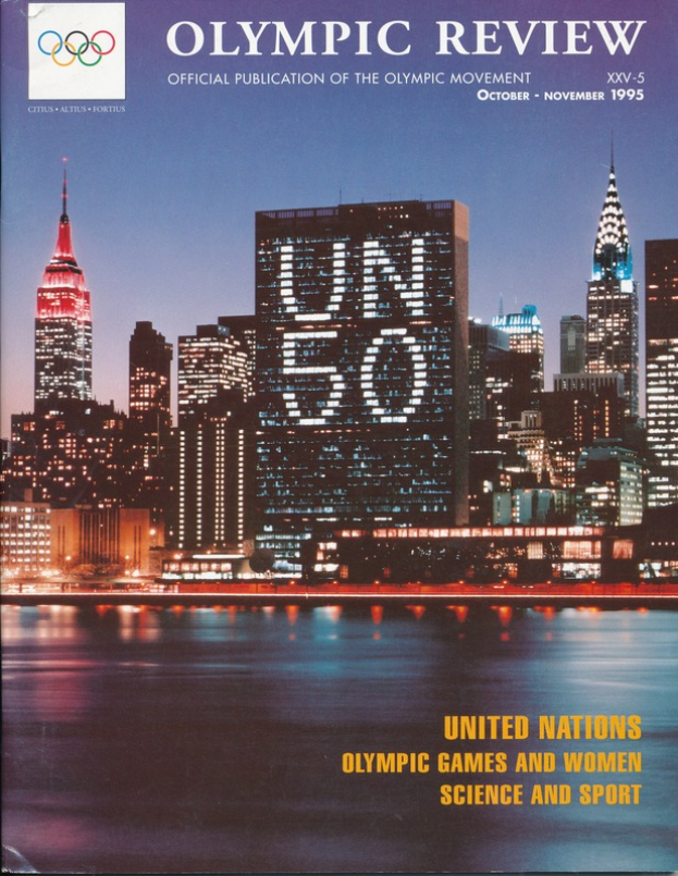 Ein Buch mit dem Titel "Olympic Review Official Publication of the Olympic Movement" liegt auf einer flachen Oberfläche, das eine Stadtlandschaft mit Gebäuden, Lichtern und Wasser auf dem Cover zeigt, mit dem Text "United Nations Olympic Games and Women Science and Sport" ebenfalls sichtbar.
