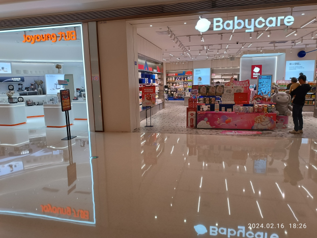 Babycare-Laden im Innern des Mall of Asia mit Menschen, Spielzeugen, Regalen, Schildern, Anzeigebildschirm und Deckenleuchten.
