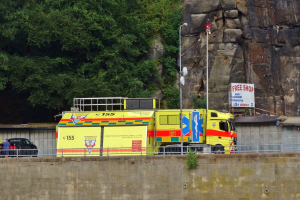 Ambulanz am Straßenrand neben einer Klippe geparkt, mit verschiedenen Gegenständen und Bäumen im Hintergrund.