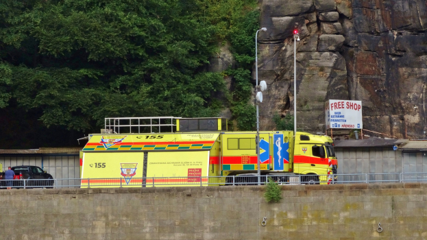 Ambulanz am Straßenrand neben einer Klippe geparkt, mit verschiedenen Gegenständen und Bäumen im Hintergrund.