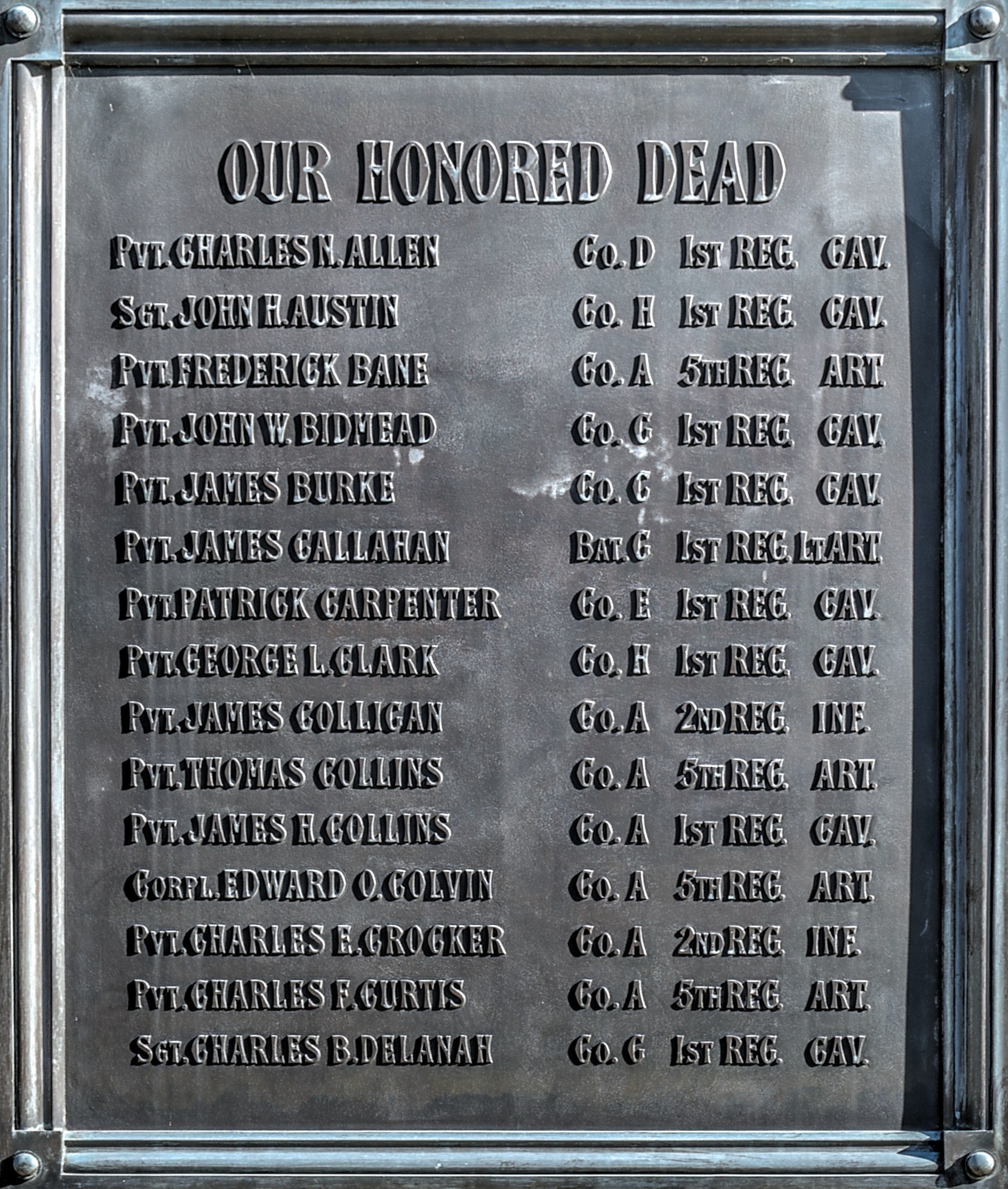 Bronzene Gedenktafel an der Außenseite eines Gebäudes mit der Inschrift "Unsere Ehrenvollen Toten".