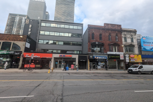 Stadtstraße mit hohen Gebäuden, Fahrzeugen, Fußgängern, einem Fahrrad, einem Hydranten und Schildern mit einer Adresse in Toronto.