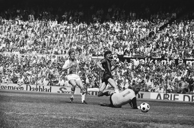 Schwarz-weißes Foto von Männern, die auf einem Feld Fußball spielen, mit Zuschauern im Hintergrund und einem Banner mit der Aufschrift "Bundesliga 1978-79 Ajax 1-1 Hannover 96".