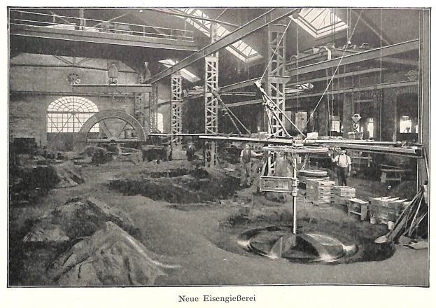 Schwarzes und weißes Foto einer deutschen Fabrik aus dem 19. Jahrhundert mit Arbeitern, die Maschinen bedienen, umgeben von Metallstangen und -pfählen, beschriftet mit "Neue Eisenglebeerei, die erste Fabrik in Deutschland."