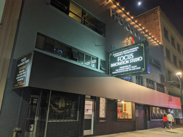 Das Focus Innovation Studio in New York City bei Nacht, mit beleuchteten Gebäuden, Menschen auf dem Gehweg und einem sichtbaren Himmel im Hintergrund.