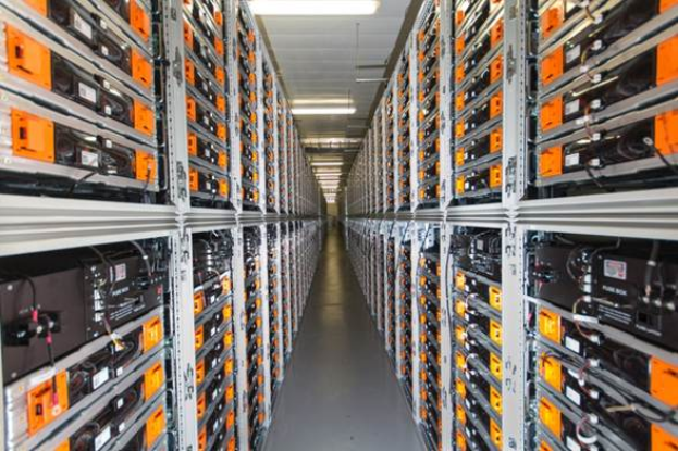 Eine lange Reihe von Servern in einem Rechenzentrum, mit elektronischen Geräten in den Gestellen und Lampen oben.