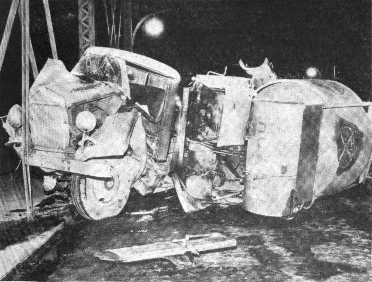Ein Schwarz-Weiß-Foto eines umgestürzten Autos am Straßenrand mit Metallstangen und einem Laternenpfahl im Hintergrund, beschriftet mit "1930er Jahre Autounfall."