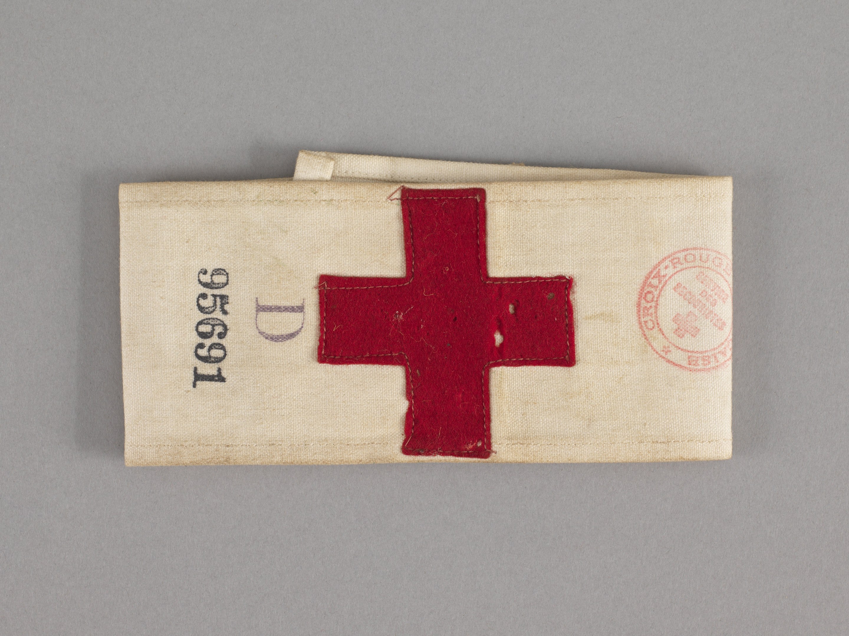 Ein rotes Kreuz-Ersthelfer-Set mit einem Text- und Stempel-behafteten Stoffbeutel, der auf einer Oberfläche liegt.