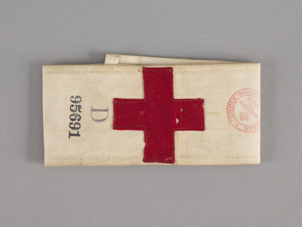 Ein rotes Kreuz-Ersthelfer-Set mit einem Text- und Stempel-behafteten Stoffbeutel, der auf einer Oberfläche liegt.