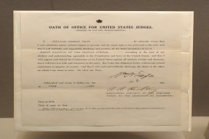 Ein Blatt mit dem Text "Amtseid für US-Richter" liegt auf einem Tisch vor einer Wand.